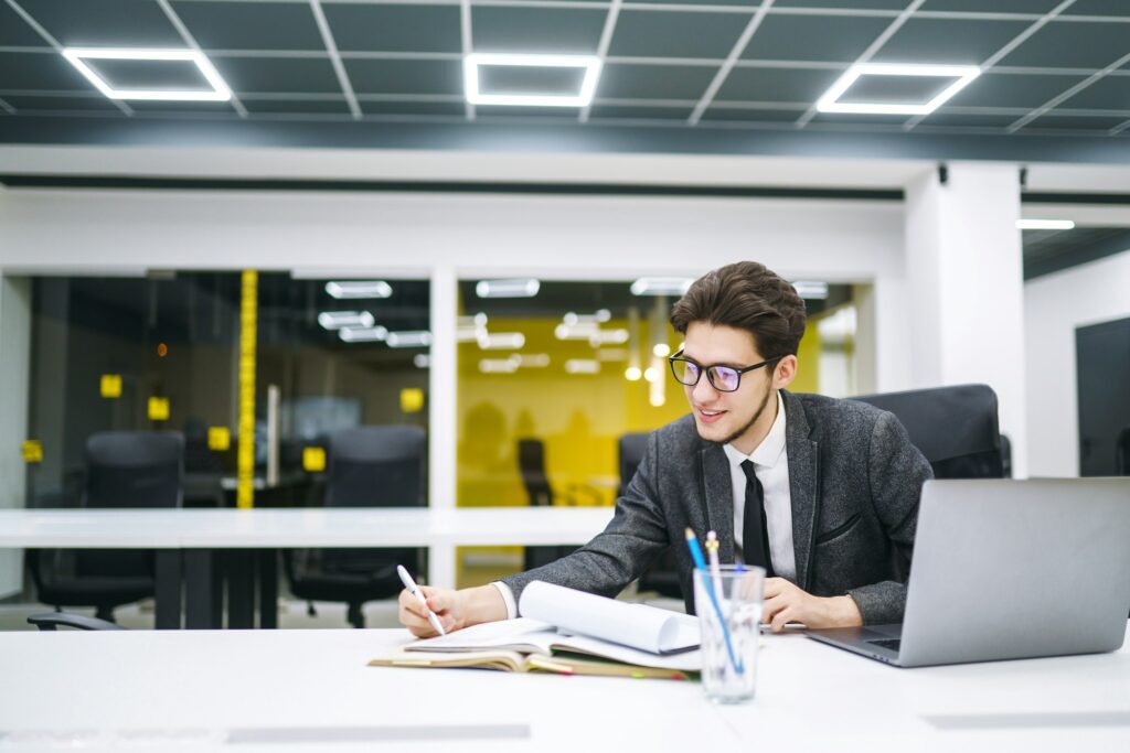 Young office manager working with papers and computer working at office. Man in a suit working.